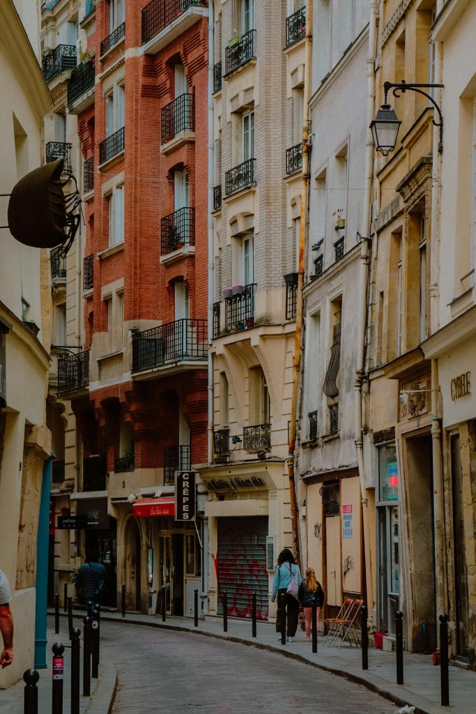 A picturesque street in Paris's Marais district featuring classic architecture and pedestrians on the sidewalk.